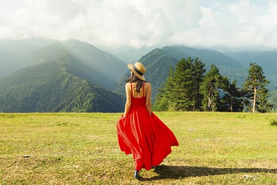 Elegant pretty woman wear red dress walk on green meadow high mountains