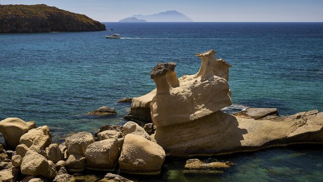 An ocean rock surrounded by a distant boat on the horizon and deep blue water, Aspragremna, White Cliffs, Mavorspilia Beach, Kimolos Island, Kimolos, Cyclades, Greek Islands, Greece