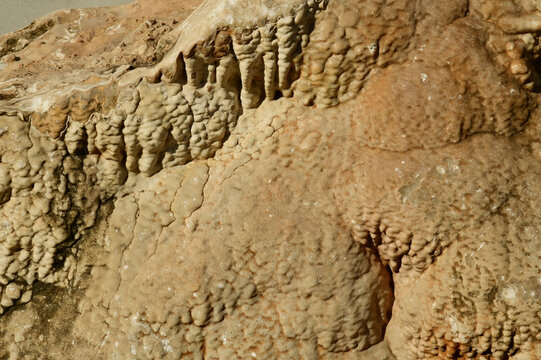 Flowstone, a type of cave formation created by thin sheets of mineral-rich water flowing down walls or floors.Formation: Water carrying dissolved minerals, usually calcite, 