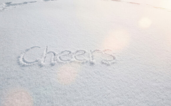 The word Cheers written in fresh white snow with sunlight glowing for winter greeting and celebration concepts