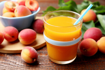Apricot juice in glass, fresh fruits and leaves on wooden table, closeup © New Africa