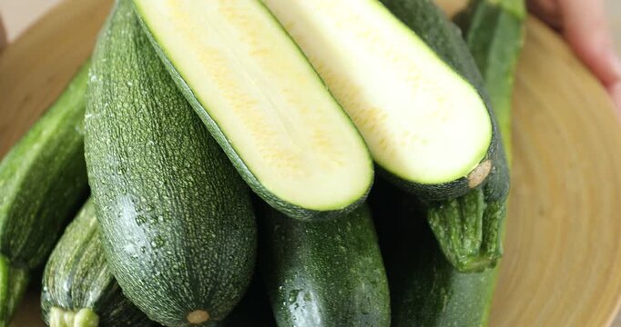 Woman with many fresh raw zucchinis on plate, closeup