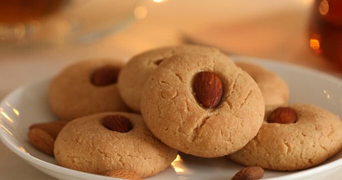 Tasty cookies with almonds on light table against blurred lights, closeup. Camera moving down