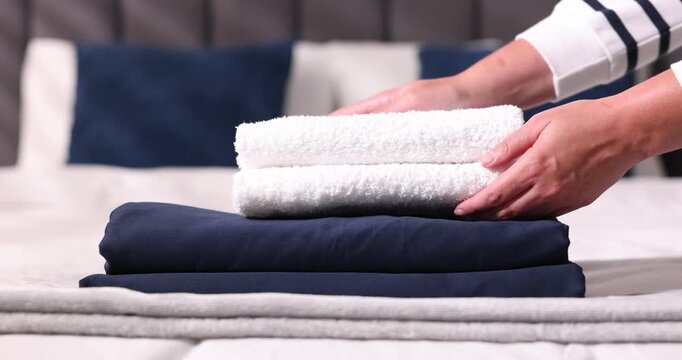 Woman putting fresh towels on bed at home, closeup