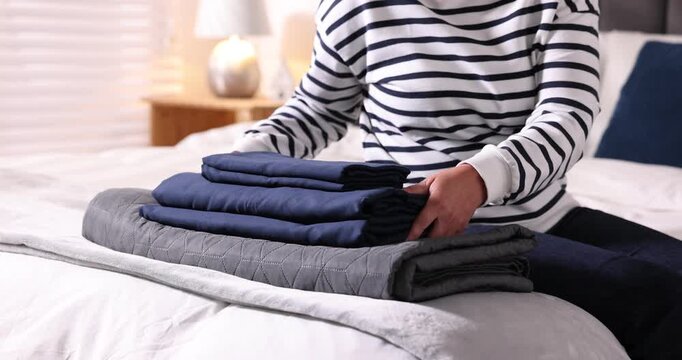 Woman putting fresh linens on bed at home, closeup