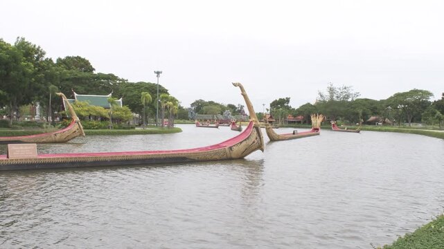 traditional ornate thai royal barges floating along a wide scenic canal surrounded by green trees