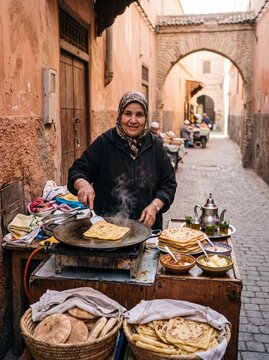 Moroccan woman cooking traditional msemen flatbread on street market.