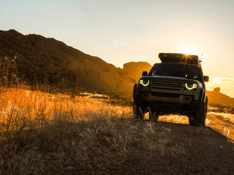 Off-road vehicle driving in desert at sunset banner copy space