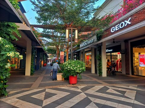 Karawang, Indonesia - August 11, 2026: Modern outdoor walkway and premium retail storefronts of Geox and Mango Outlet at Summarecon Villaggio Outlets shopping mall.