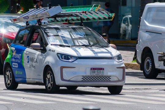 ZAPOPAN, MEXICO - AUGUST 28, 2026: Megacable JAC E10X electric service car driving carrying extension ladders.