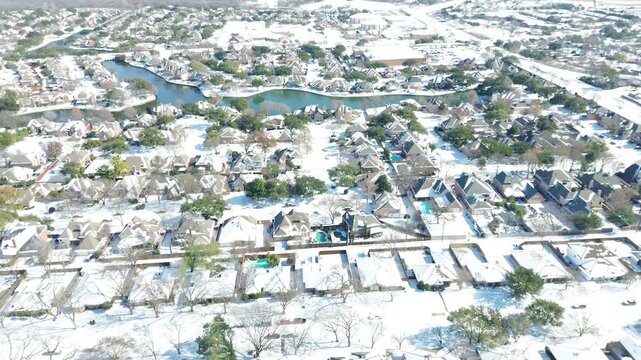 Meandering retention canals wind behind suburban housing tracts across DFW metroplex. Sparkling white snow blankets waterfront properties, neighborhood rooflines in Coppell, Texas