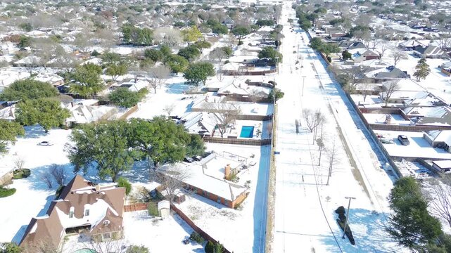 Snow blankets East Sandy Lake Road corridor past DFW metroplex residential subdivisions. Icy roadways flank snowpack rooftops, highlighting severe winter storm impacts in Coppell, Texas