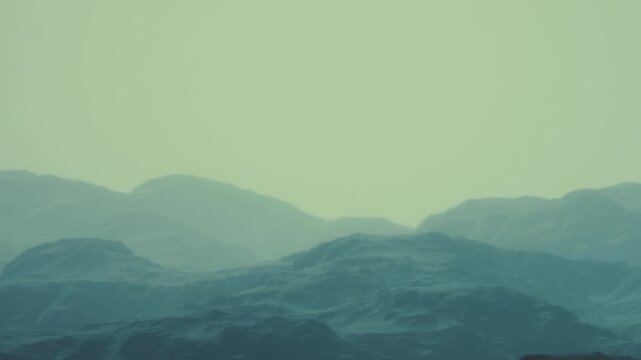 Foggy mountains appear layered in shades of blue. The scene shows a distant view of hills and rocky terrain in a remote area with low visibility. The weather seems to be overcast.