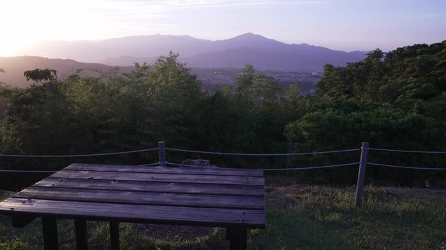 Wooden bench table at a park overlook with sunset light casting over distant mountains