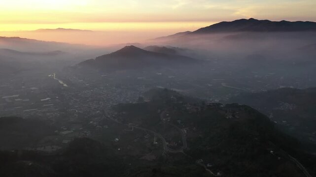 Aerial drone view of D&rsquo;Ran Pass and D&rsquo;Ran in Lam Dong, Vietnam, glowing in the first light of sunrise, with winding mountain roads, green valleys and misty highlands.