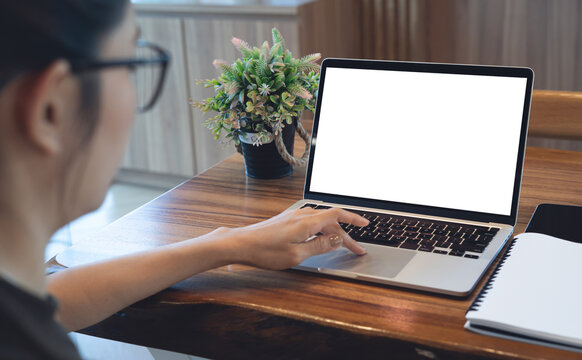 Mockup laptop with blank screen, woman working on laptop on wooden desk, remote work in workspace concept. Close up