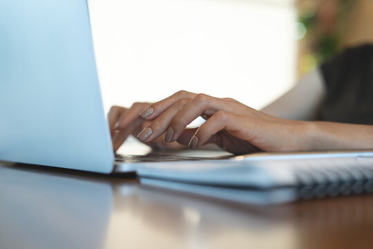 Close up of woman hands typing on laptop with notebook on desk, remote work in modern workspace with copy space, online business concept