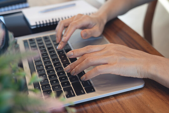 Close up of woman typing on laptop  at wooden desk, remote work, online business concept.