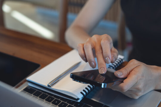 Close up of woman using smartphone over laptop and notebook, modern remote work and digital communication concept.