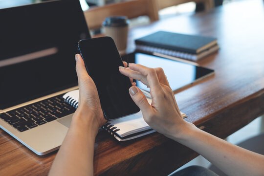 Close up of woman using smartphone on desk with laptop and notebook, modern remote work and digital lifestyle concept.