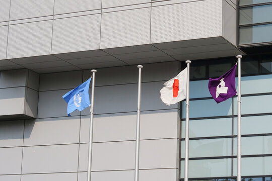 TOKYO, JAPAN - April 16, 2026: Three flags flag flying in front of Bunkyo Civic Center in Tokyo: the United Nations, the Japanese flag and the flag of Bunkyo Ward.