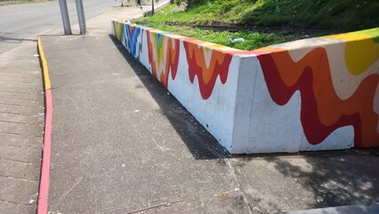 Colorful abstract mural on a concrete wall next to a sidewalk and road © NoblePix
