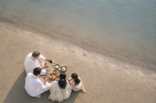 Indian family performing traditional pitru paksha pinda daan on riverbank