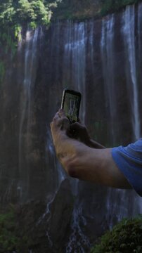 Person taking video of tumpak sewu waterfall in indonesia