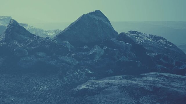 Two large mountains stand firm in a misty landscape. The scene shows soft shadows and cool colors. It captures the quiet beauty of natures rock formations.