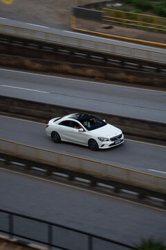 High-Angle View of a White Mercedes-Benz CLA Driving on an Urban Highway