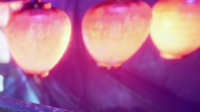 Lanterns glow brightly in a vibrant display during a night festival in the city. The colors light up the surroundings and attract many visitors enjoying the event.