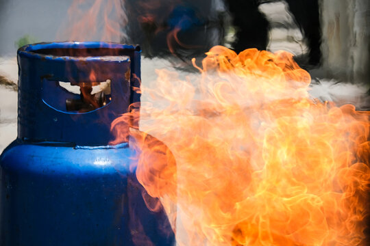 A dangerous fire and flames bursting out from a blue cooking gas cylinder, representing a fire hazard, industrial accident, and household safety emergency.safety content