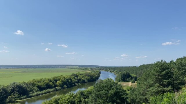 Scenic landscape view of the Don River flowing through green hills and forests in Semiluksky District, Voronezh Oblast, Russia, under a clear blue summer sky, representing rural tourism and natural be