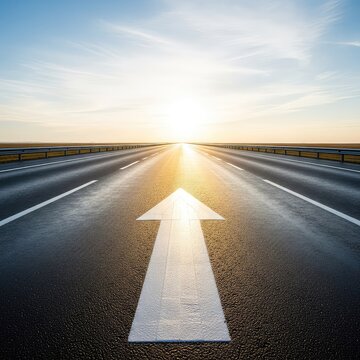 A wide asphalt road stretches toward a distant horizon under a bright sky, featuring a white painted arrow pointing forward on the pavement, sky, direction, arrow