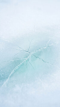 Cracks on frozen surface create delicate on icy blue texture with soft light and cold atmosphere