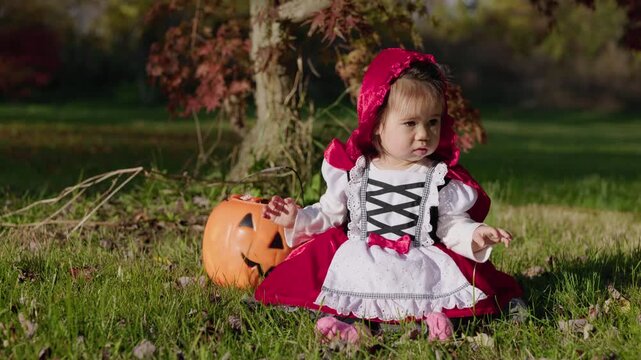 Toddler in Red Riding Hood Costume Beside Jack-o-Lantern