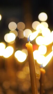 Close up view of a single yellow prayer candle burning with a warm, gentle flame, creating a spiritual atmosphere with a background of beautiful, soft focus bokeh lights