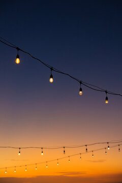Outdoor String Lights Glowing Against a Vibrant Tropical Sunset Sky