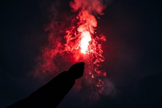 Person Holding Bright Red Emergency Distress Flare at Night