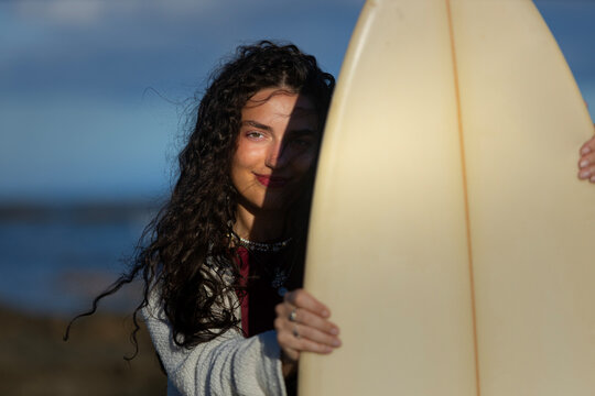 Young woman holding surfboard on the beach with copy space