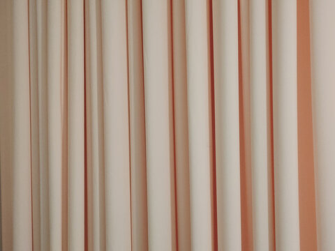 warm vertical striped curtain fabric with alternating cream and muted reddish-orange folds, providing a clean abstract interior textile background for interior design, decoration, privacy, and archite