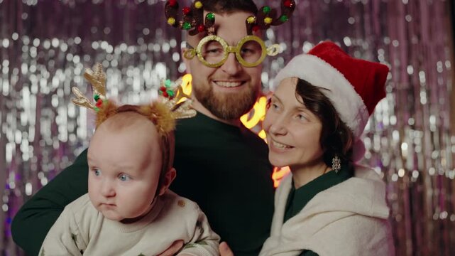 A joyful family celebrating Christmas with their baby, dressed in festive costumes and hats. They are enjoying the holiday season with smiles and laughter, creating precious memories. Happy Family
