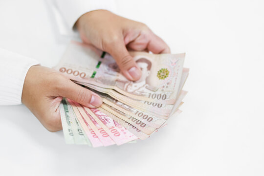 Woman holding Thai baht banknotes, representing finance, income, salary, savings, investment, money, cash, spending, personal budgeting, and everyday economic concepts, close-up