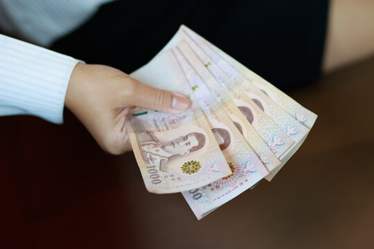 Working woman or Office lady holding Thai baht banknotes, representing finance, income, salary, savings, investment, money, cash, spending, personal budgeting, and everyday economic concepts, close-up