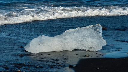 A close-up view of ice fragments from Vatnajokull glacier resting along the shore of Diamond Beach, Iceland, creating a beautiful natural scene with contrasting ice and black sand. © Asanee