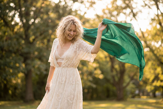 Young white woman holding green fabric in sunny park