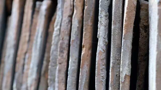 Close-up slide shot of stacked old clay roof tiles showing rough texture, weathered edges, and stacked parallel lines for construction.