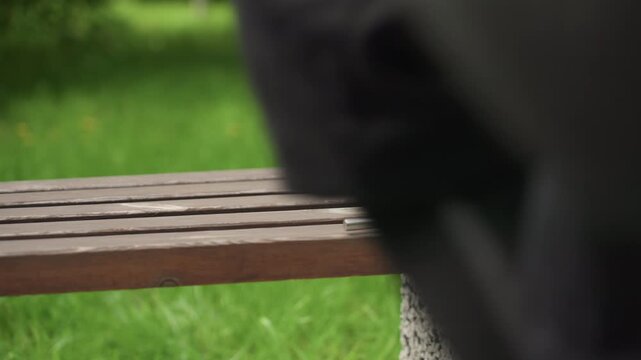 Close up of two medieval swords and fencing foil arranged on wooden bench in park setting. Sword with leather wrapped hilt placed alongside rapier both resting horizontally later hand