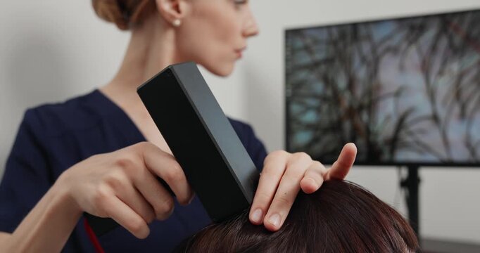 Professional scalp imaging and hair clinic examination showing patient reclined with monitor display for medical consultation of trichologist.