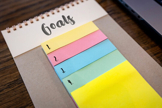 Close up of colorful numbered sticky notes under Goals notebook heading, planning and to do list concept